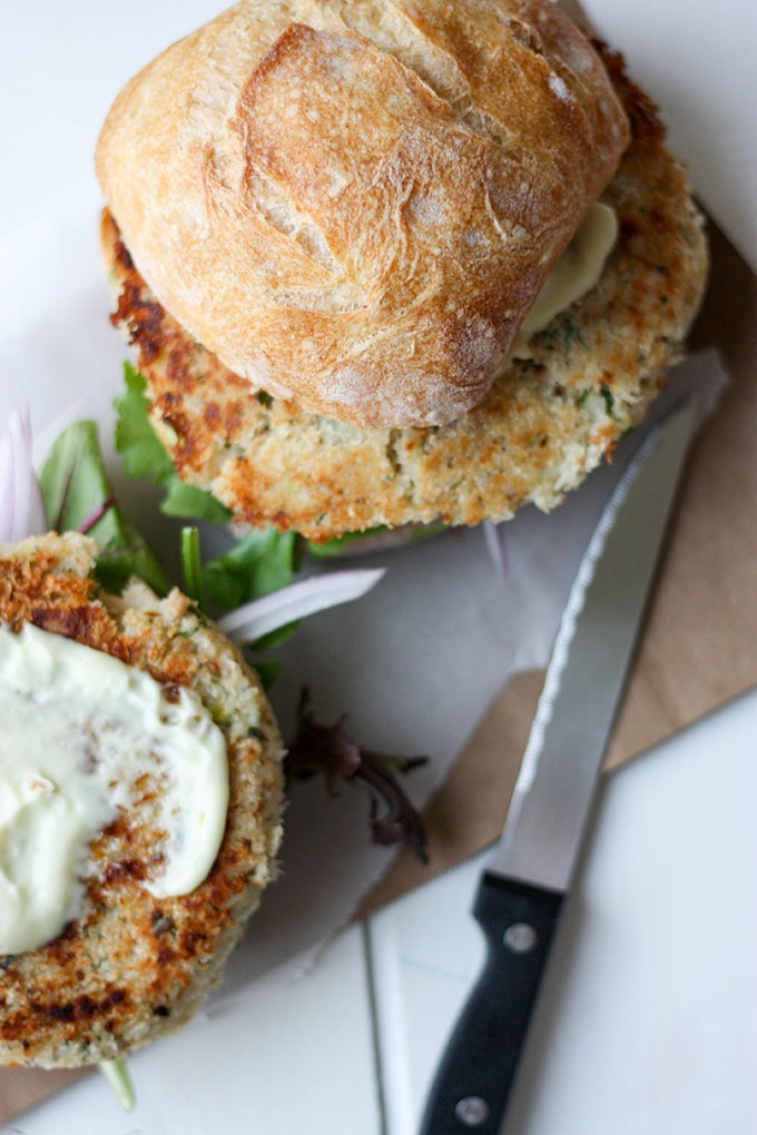 steak knife next to salmon burger topped with ciabatta bun on brown paper