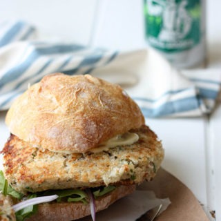 salmon burger topped with a ciabatta roll on a brown piece of paper