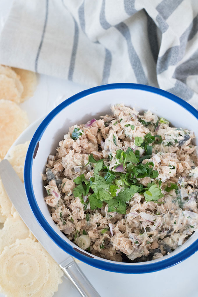 white bowl with blue rim, crackers on left hand side, bowl filled salmon dip