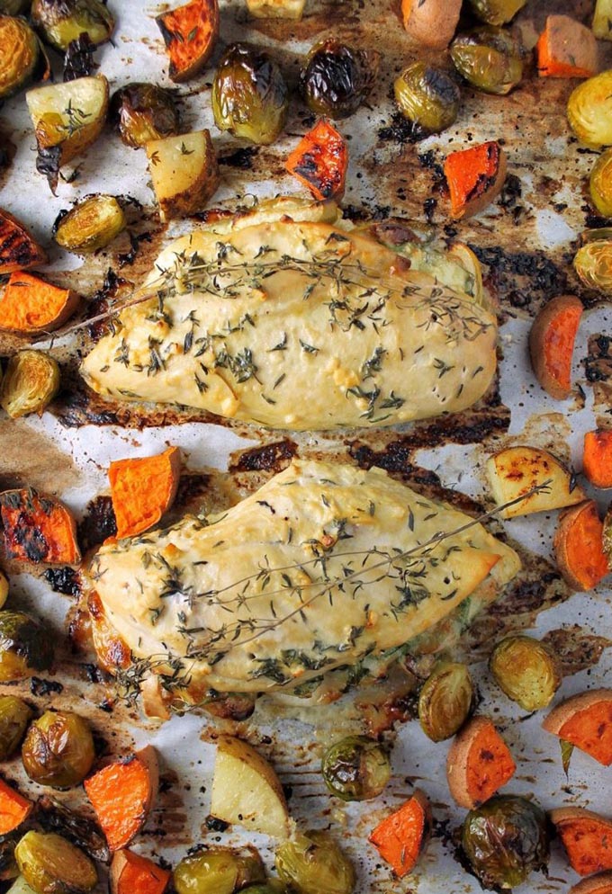 sheet pan stuffed chicken surrounded by vegetables on baking tray