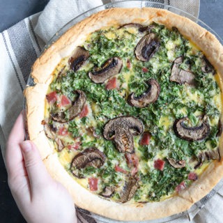 hand holding quiche in glass dish