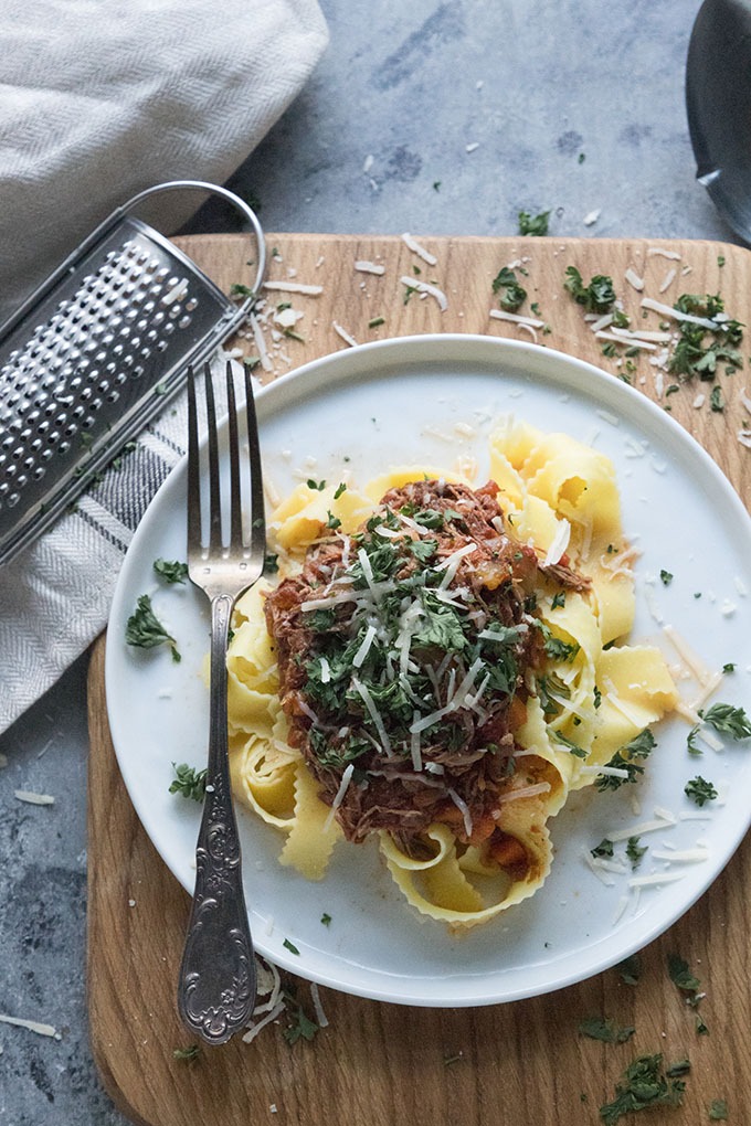 plate of slow cooker beef ragu on wooden board