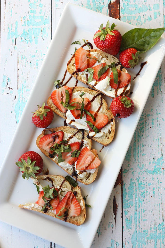 long white rectangular plate of strawberry bruschetta on a turquoise board