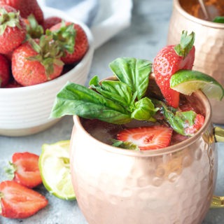 two strawberry basil mule mugs on a grey board