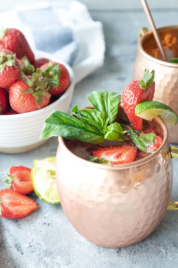 two strawberry basil mule mugs on a grey board