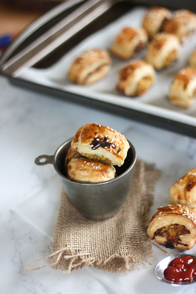 thai chicken sausage rolls in antique metal cup, tray of sausage rolls in background