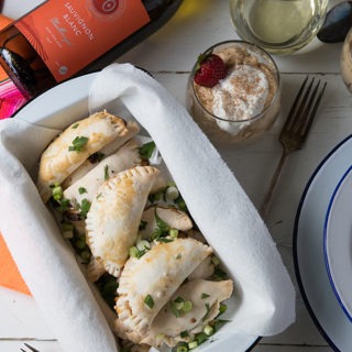 empanadas in an enamel loaf tin, below bottle of white wine and dulce de leche mousse pots