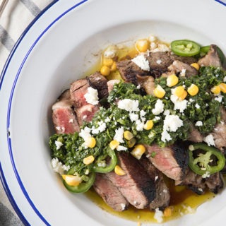 steak with chimichurri sauce on a blue and white enamel plate