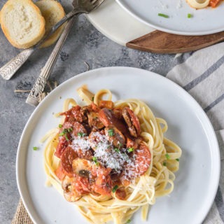 tomato chorizo pasta on white plate