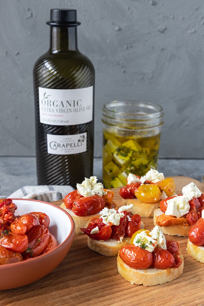 tomato crostinin on wooden board with tomatoes, olive oil and feta