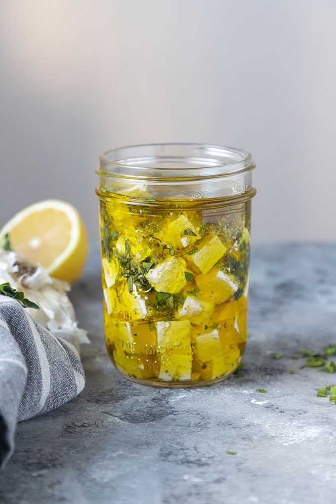 marinated feta in jar on grey board