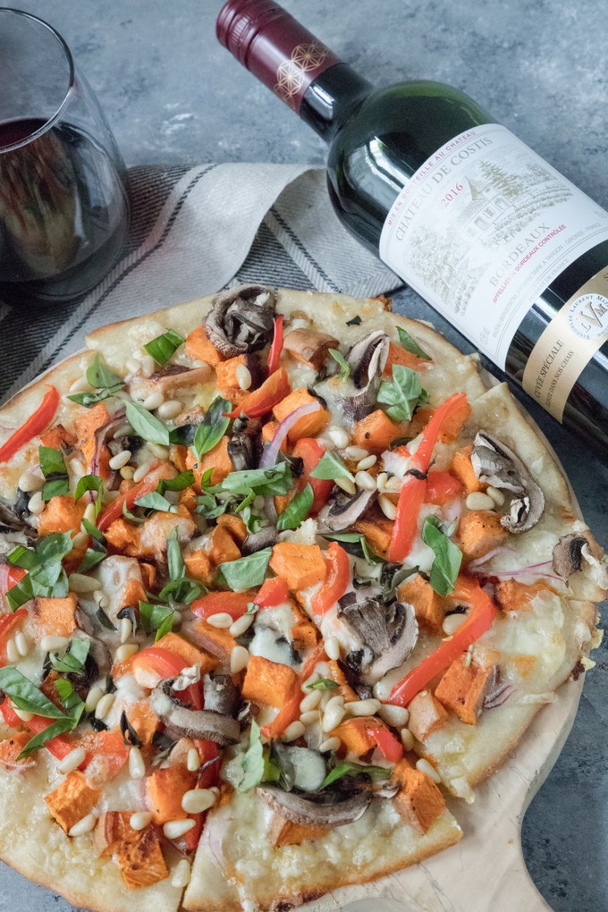 veggie pizza on wooden board with bottle of wine