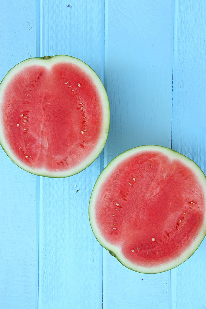 two watermelon halves on a bright blue wooden board