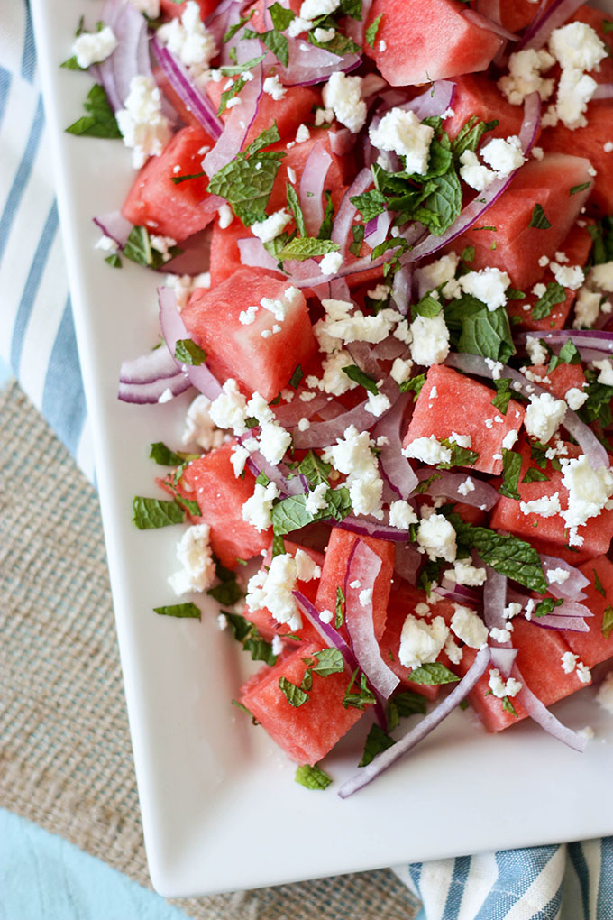 watermelon mint feta salad on a white plate; white plate is set on a blue and white napkin