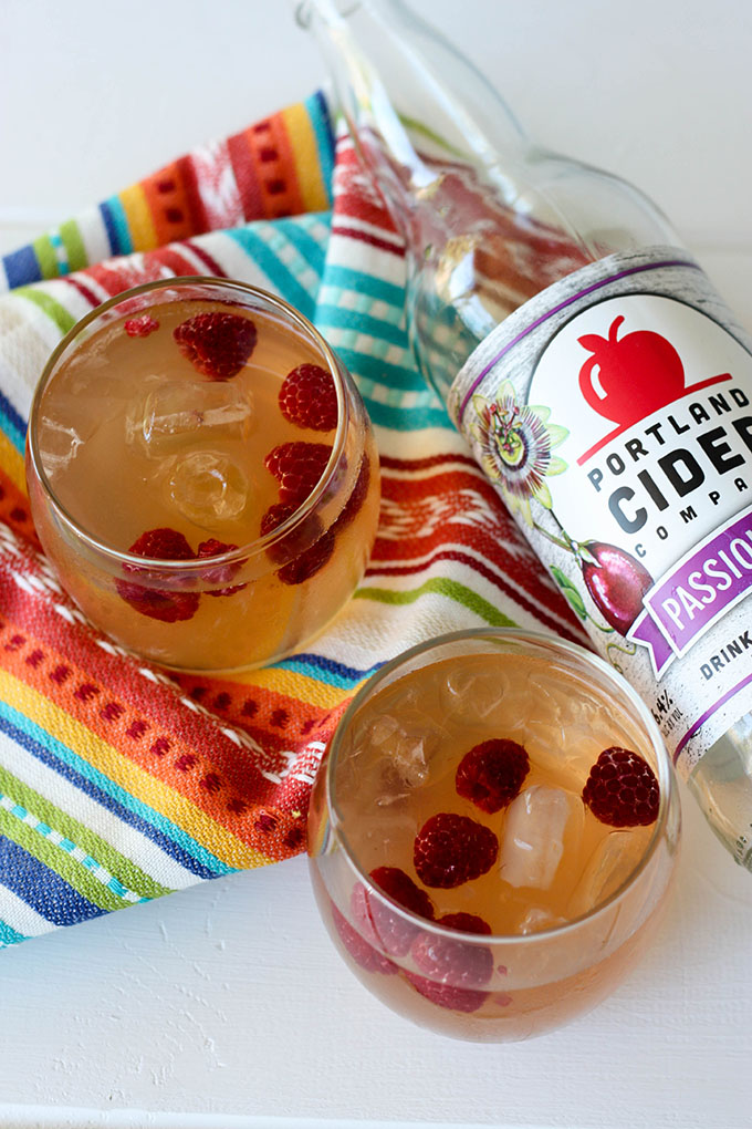 close up overhead of two glasses of passion fruit cider punch on colourful napkin